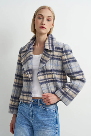 A woman wearing a blue plaid flannel jacket and blue jeans on a white background.