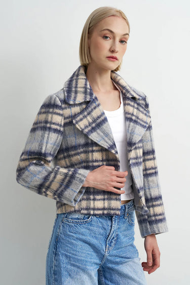 A woman wearing a blue plaid flannel jacket and blue jeans on a white background.