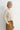 A woman wearing an embellished cream knit sweater and mustard yellow pants on a white background.