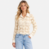 A woman wearing a sheer lace blouse in cream and black jeans on a white background.