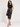 A woman wearing a black tank top and a silver studded black sequin midi skirt with black open  heels on a studio background
