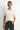 Woman wearing a white knit top and black pants against a white background