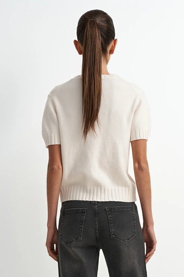 Person wearing a white sweater and black pants on a white background