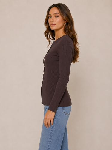 A woman modeling a dark brown ribbed cardigan with front buttons, paired with light blue jeans, against a plain beige studio background.