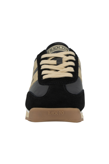 A front view of a gold and black sneaker on a white background
