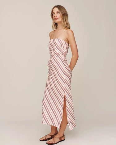 Woman wearing a strapless red and white striped dress on a plain background