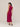Woman wearing a sleeveless burgundy dress on a plain background