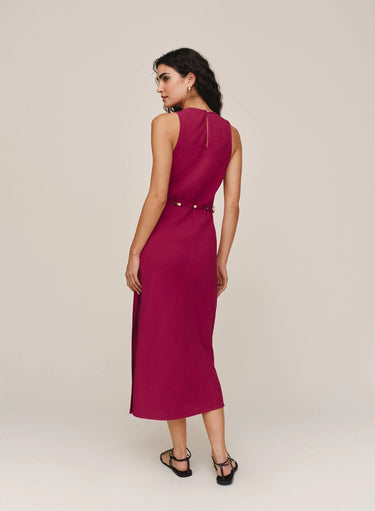 Woman wearing a sleeveless burgundy dress on a plain background