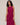 Woman wearing a magenta sleeveless dress with button details on a beige background