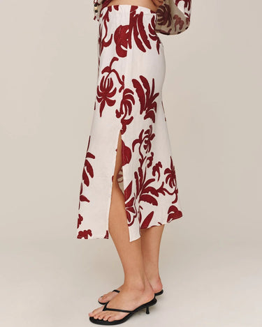 White skirt with red floral pattern worn by a person on a plain background