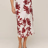 Person wearing a white skirt with red floral pattern on a plain background