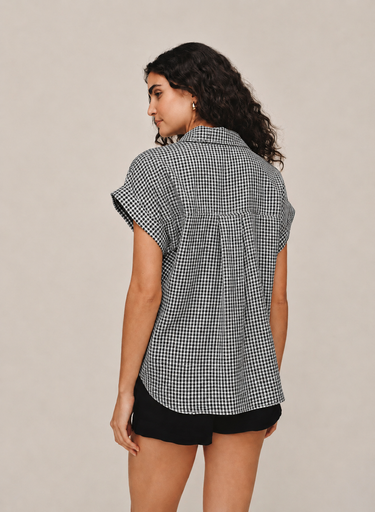 Woman wearing a black and white checkered shirt with short sleeves on a beige background