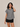 Woman wearing a black and white checkered shirt and black shorts on a beige background