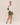 Woman wearing a white shirt, green skirt, and black shoes on a beige background
