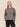 A woman wearing A slouchy metallic crewneck sweater with black jeans on a studio background.