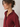 A woman in profile wearing a burgundy button-down shirt and gold hoop earrings against a plain light background.