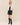 A front view of a model wearing a black top, a black leather skirt and black leather boots with a cropped leather bomber jacket.