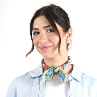 Woman wearing a colorful green floral scarf around her neck on a white background
