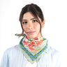 Woman wearing a colorful green floral scarf on a white background