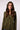 A woman models an olive green blazer with a knit hood against a plain light background.