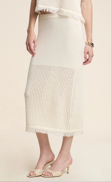 Person wearing a white textured skirt on a beige background