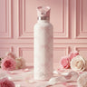 White water bottle with floral design on a pink background with roses