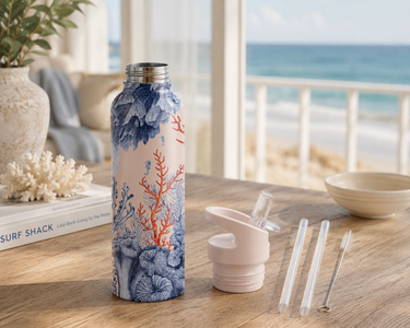 Tumbler with coral design on a table by a window with a view of the ocean.