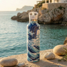 Decorative water bottle with wave design on a rocky beach