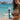 Woman holding a blue wave-patterned water bottle on a beach