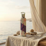 Decorative water bottle with floral design on a table by a window with curtains.