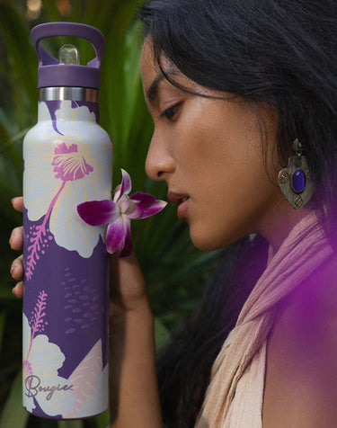 Woman holding a purple water bottle with floral design against a green leafy background