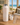Pink Palm tree-patterned water bottle with accessories on a table with a beach view.