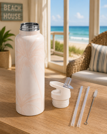 Pink Palm tree-patterned water bottle with accessories on a table with a beach view.
