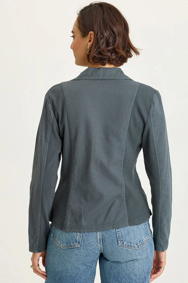 Person wearing a gray jacket and blue jeans on a white background