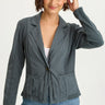Woman wearing a gray blazer over a white top and blue jeans on a white background