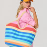 Woman holding a colorful striped tote bag against a plain background