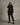 Person wearing a black suit holding a camera against a plain background