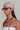 Woman wearing a patterned headscarf, sunglasses, and a long red necklace against a plain background