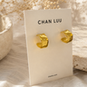 Textured gold cuff hoop earrings on branded cardstock on a neutral background.