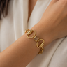 A gold horsebit chain bracelet with a clear square-cut gemstone in the center