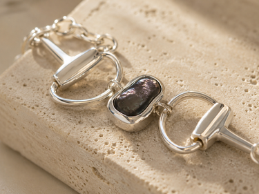 a horsebit bracelet with a peacock pearl stone in the center