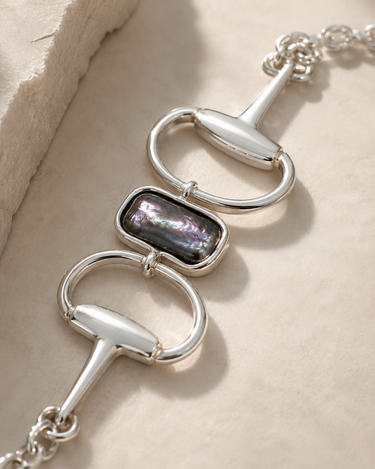 a horsebit bracelet with a peacock pearl stone in the center