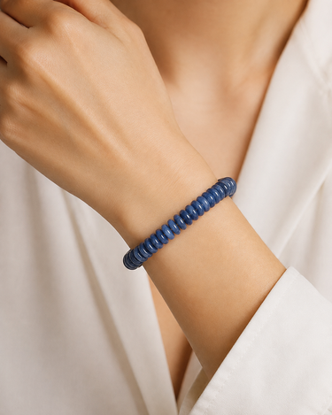 A close-up of a person's wrist wearing a dark blue beaded spiral bracelet