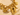 A gold-tone charm bracelet featuring a chunky link chain and multiple dangling charms, including a lock, key, shell, and coin on a neutral  background