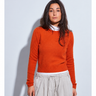 Woman wearing a bright orange crewneck sweater layered over a white mock-neck top with relaxed light beige wide-leg pants.