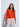 Woman wearing a bright orange crewneck sweater layered over a white mock-neck top with relaxed light beige wide-leg pants.
