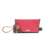 A pink glittery crossbody bag with a colorful woven strap, a decorative hanging charm, and a small gold-tone logo plaque on a white background.