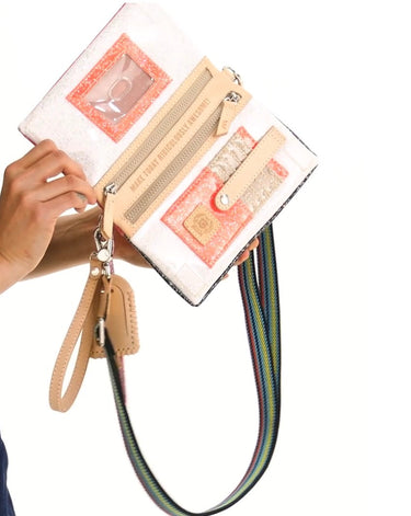 A hand holding a white textured clutch wallet with peach and beige accents, a clear ID window, card slots, and a colorful striped shoulder strap against a white background.