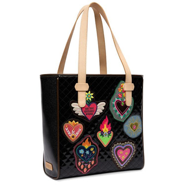 A black quilted tote bag with beige shoulder straps, decorated with multiple colorful embroidered heart patches featuring flames, wings, and floral details, shown against a plain white background.