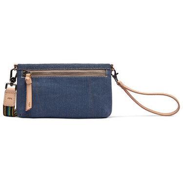 A Consuela wristlet clutch in a blue and navy striped fabric, featuring a tan leather wristlet strap, a back sipper, and a matching leather hangtag, with a colorful woven strap detail.